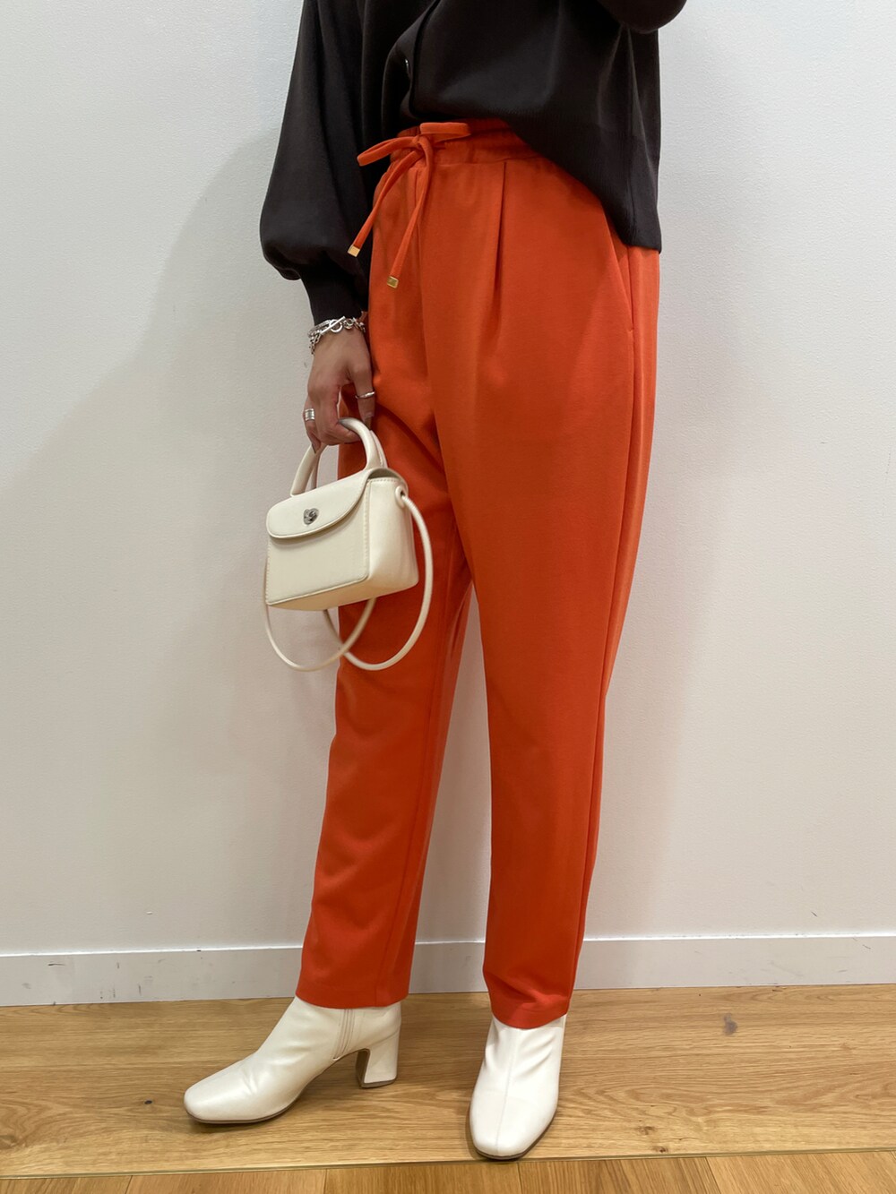 ブラウン系のカーディガン/ボレロ、オレンジ系のその他パンツ、ホワイト系のショルダーバッグを着用したレディースの秋コーディネートの4枚目の写真