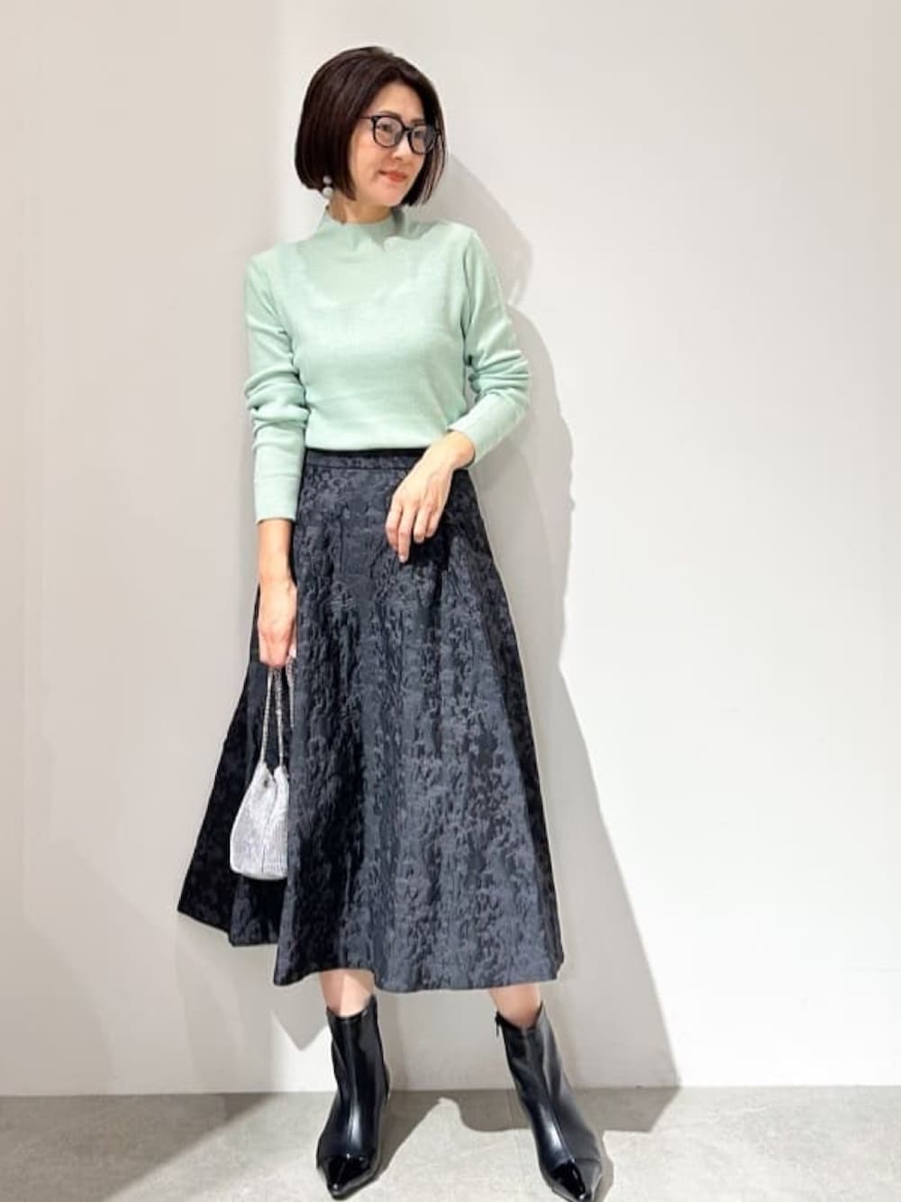 ブラック系のブルゾン、グリーン系のニット/セーター、ブラック系のスカートを着用したレディースの秋コーディネートの6枚目の写真