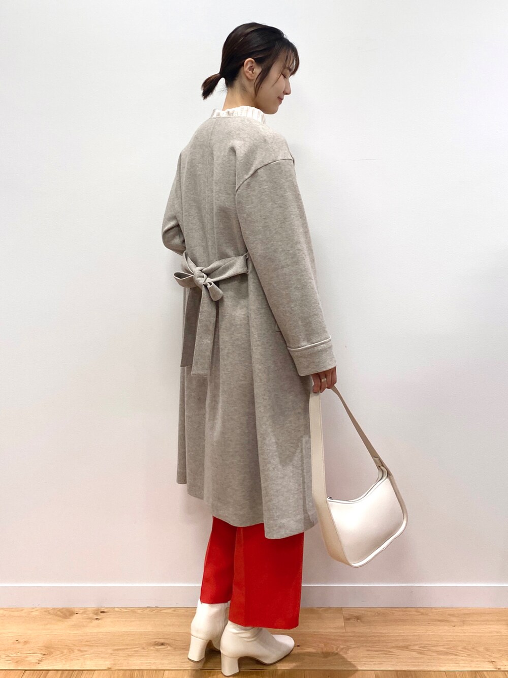 グリーン系のニット/セーター、ベージュ系のノーカラーコート、オレンジ系のその他パンツを着用したレディースの秋コーディネートの3枚目の写真