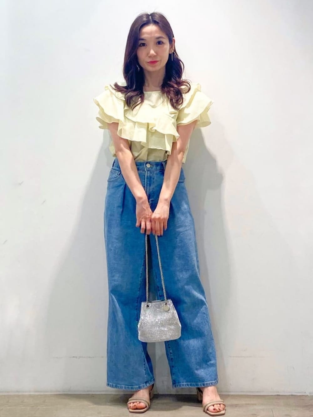 イエロー系のシャツ/ブラウス、ブルー系のデニムパンツ、ホワイト系のショルダーバッグを着用したレディースの春コーディネートの2枚目の写真