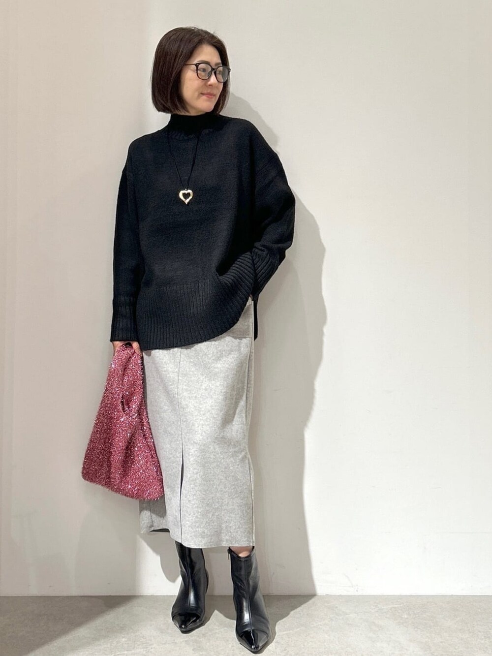 ホワイト系のノーカラーコート、グレー系のスカート、ブラック系のショルダーバッグを着用したレディースの秋コーディネートの5枚目の写真