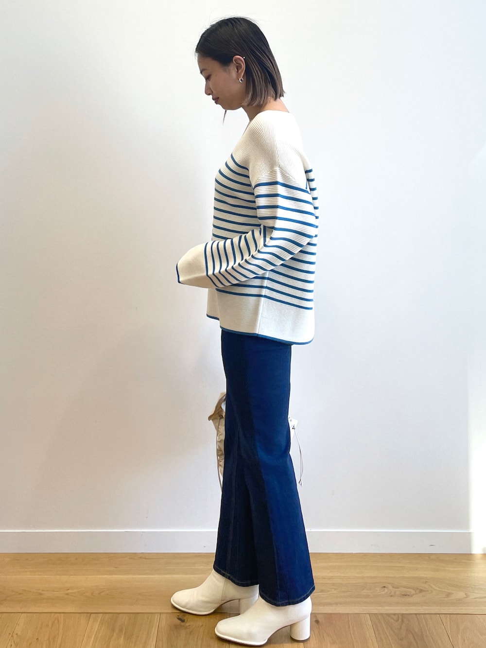 ブルー系のニット/セーター、ブルー系のデニムパンツ、ホワイト系のブーツを着用したレディースの冬コーディネートの2枚目の写真