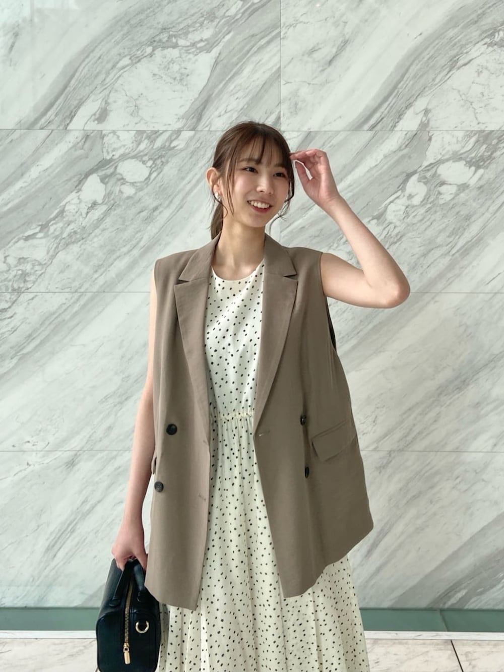 ブラウン系のベスト、ホワイト系のワンピース、ブラック系のサンダルを着用したレディースの春コーディネートの6枚目の写真