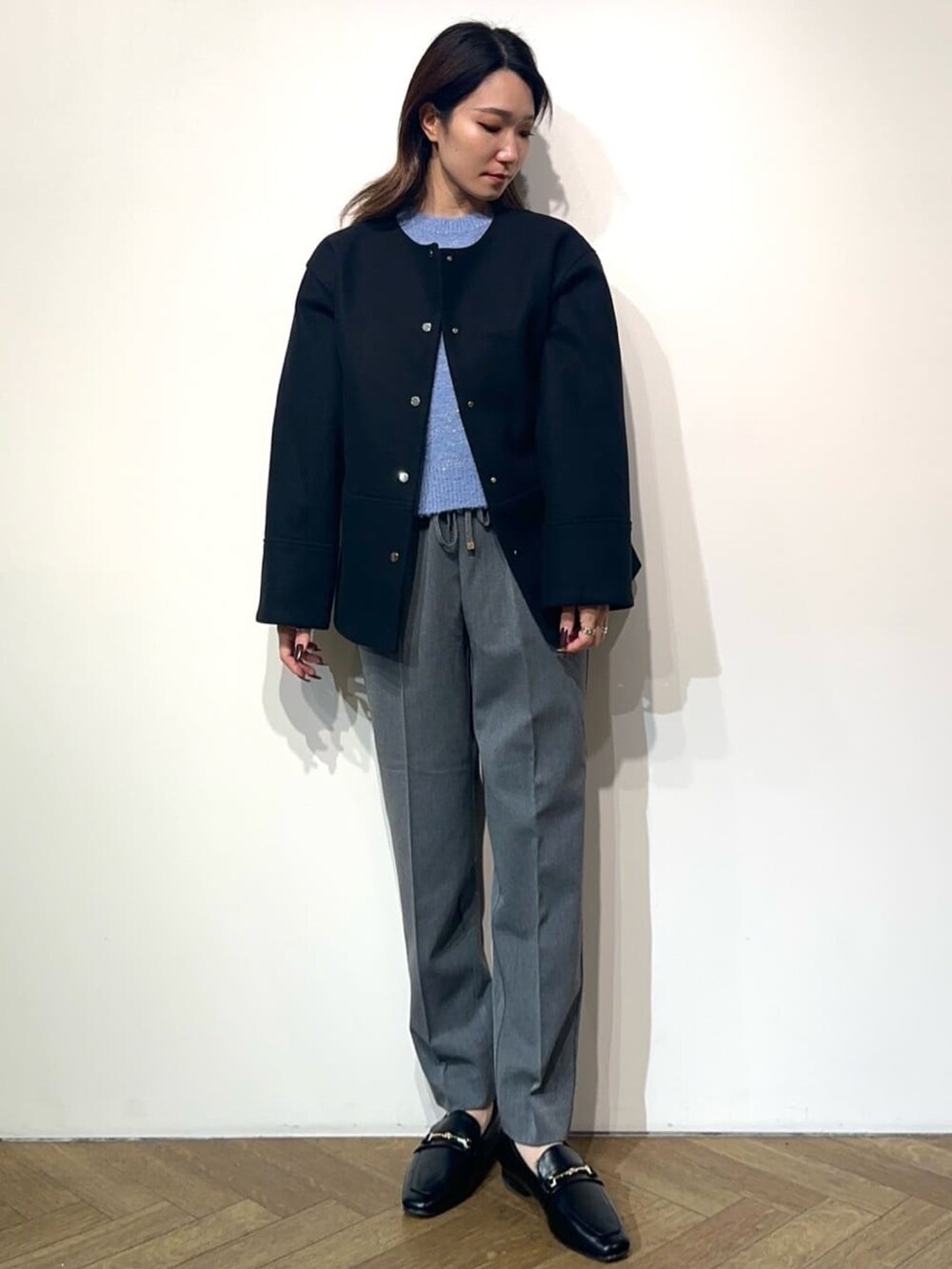 グレー系のその他パンツ、ブラック系のドレスシューズ、ブラック系のノーカラーコートを着用したレディースの冬コーディネートの2枚目の写真