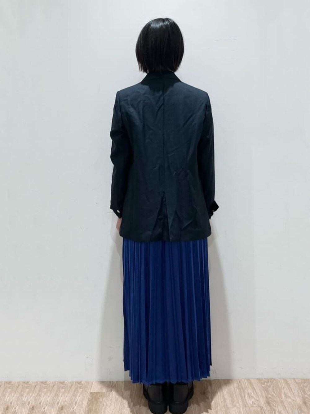 ブルー系のスカート、ブルー系のテーラードジャケット、ブラック系のニット/セーターを着用したレディースの秋コーディネートの4枚目の写真