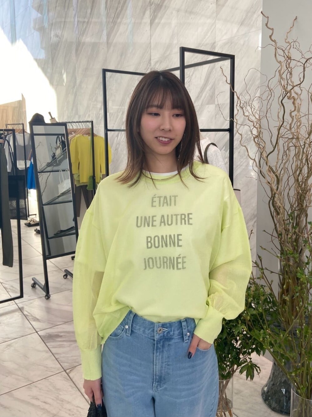 グリーン系のニット/セーター、ブルー系のデニムパンツ、ベージュ系のサンダルを着用したレディースの春コーディネートの5枚目の写真