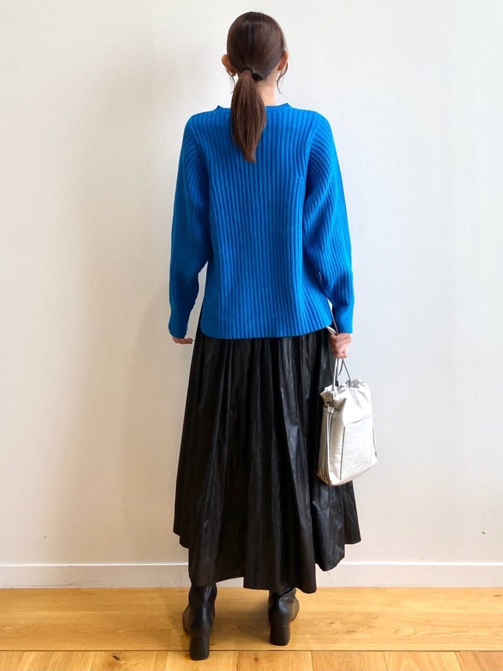 ブルー系のニット/セーター、ブラック系のスカート、ブラック系のブーツを着用したレディースの秋コーディネートの4枚目の写真