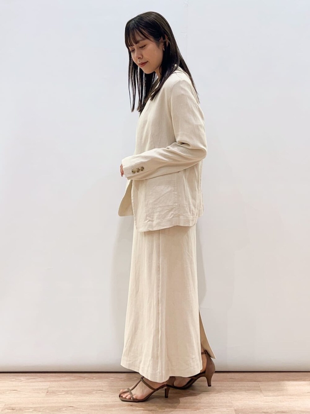 ブラウン系のサンダル、ベージュ系のスカート、ブラウン系のノーカラージャケットを着用したレディースの春コーディネートの2枚目の写真