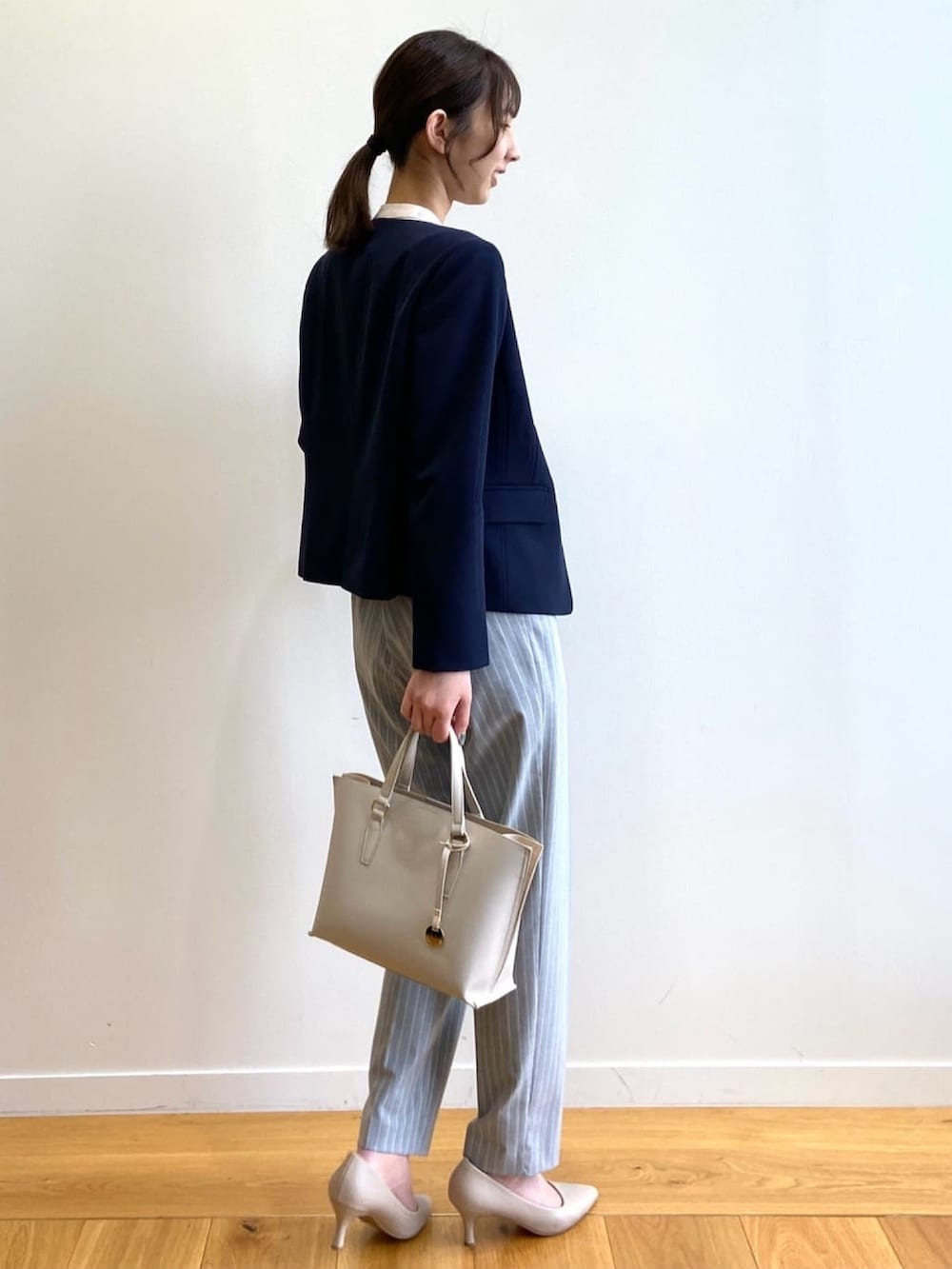 ブルー系のノーカラージャケット、グレー系のその他パンツ、ベージュ系のトートバッグを着用したレディースの春コーディネートの3枚目の写真