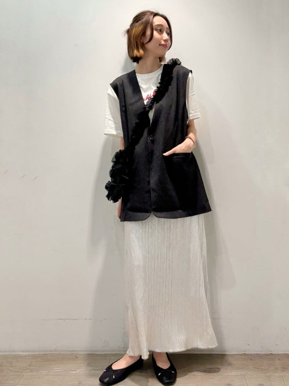 シルバー系のスカート、グレー系のベスト、ホワイト系のTシャツ/カットソーを着用したレディースの夏コーディネートの6枚目の写真