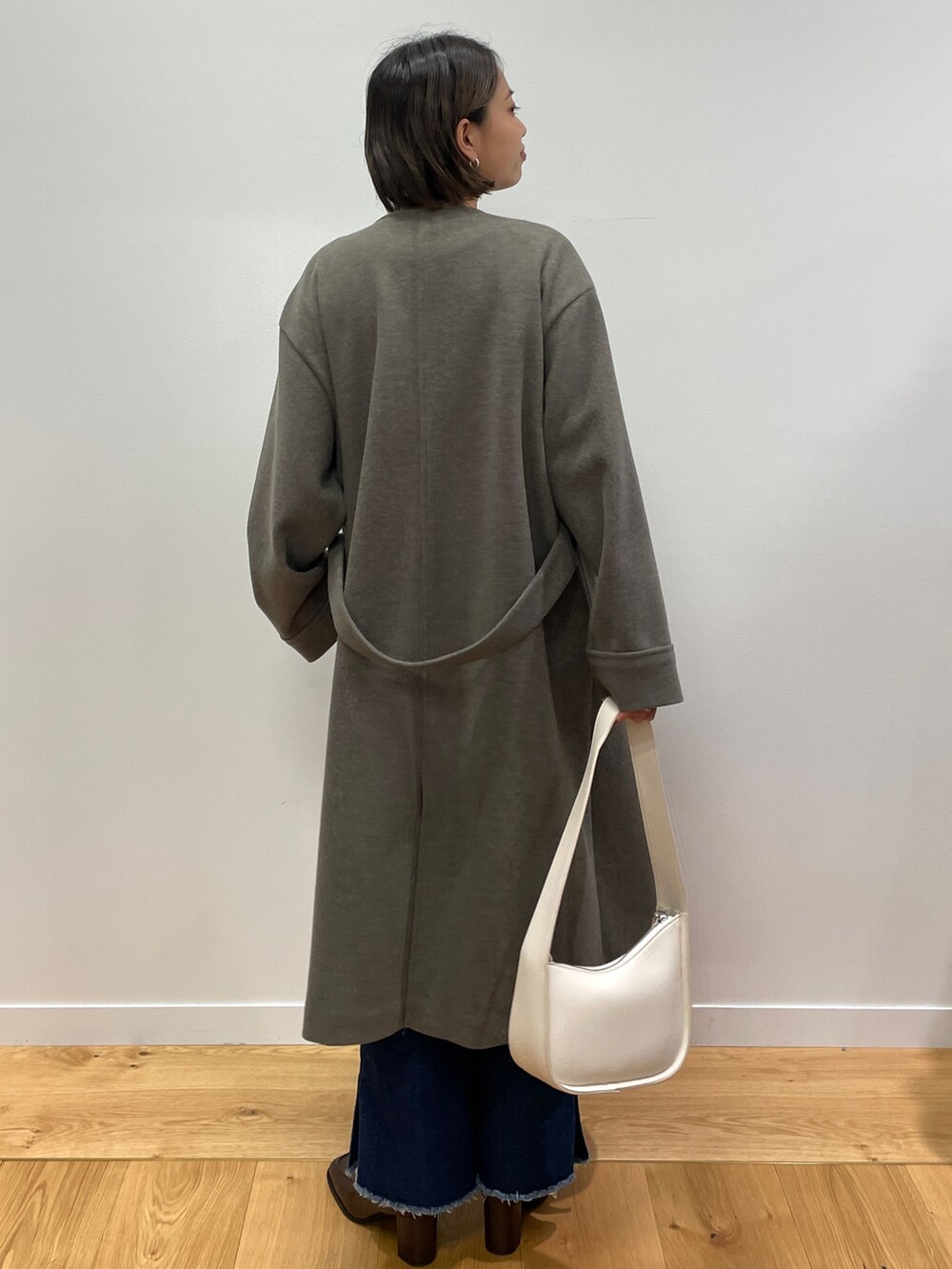 ブラウン系のノーカラーコート、レッド系のニット/セーター、ブルー系のその他パンツを着用したレディースの秋コーディネートの2枚目の写真