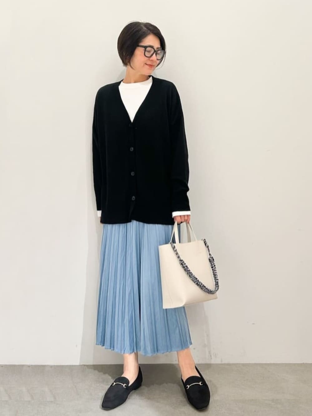 ホワイト系のショルダーバッグ、ホワイト系のチェスターコート、ブラック系のカーディガン/ボレロを着用したレディースの冬コーディネートの3枚目の写真