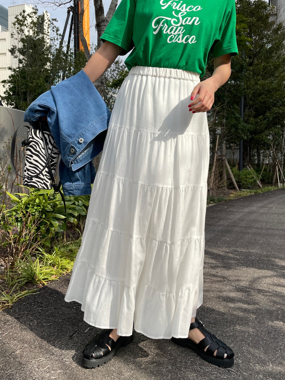 ブラック系のサンダル、ホワイト系のスカート、ホワイト系のショルダーバッグを着用したレディースの春コーディネートの4枚目の写真