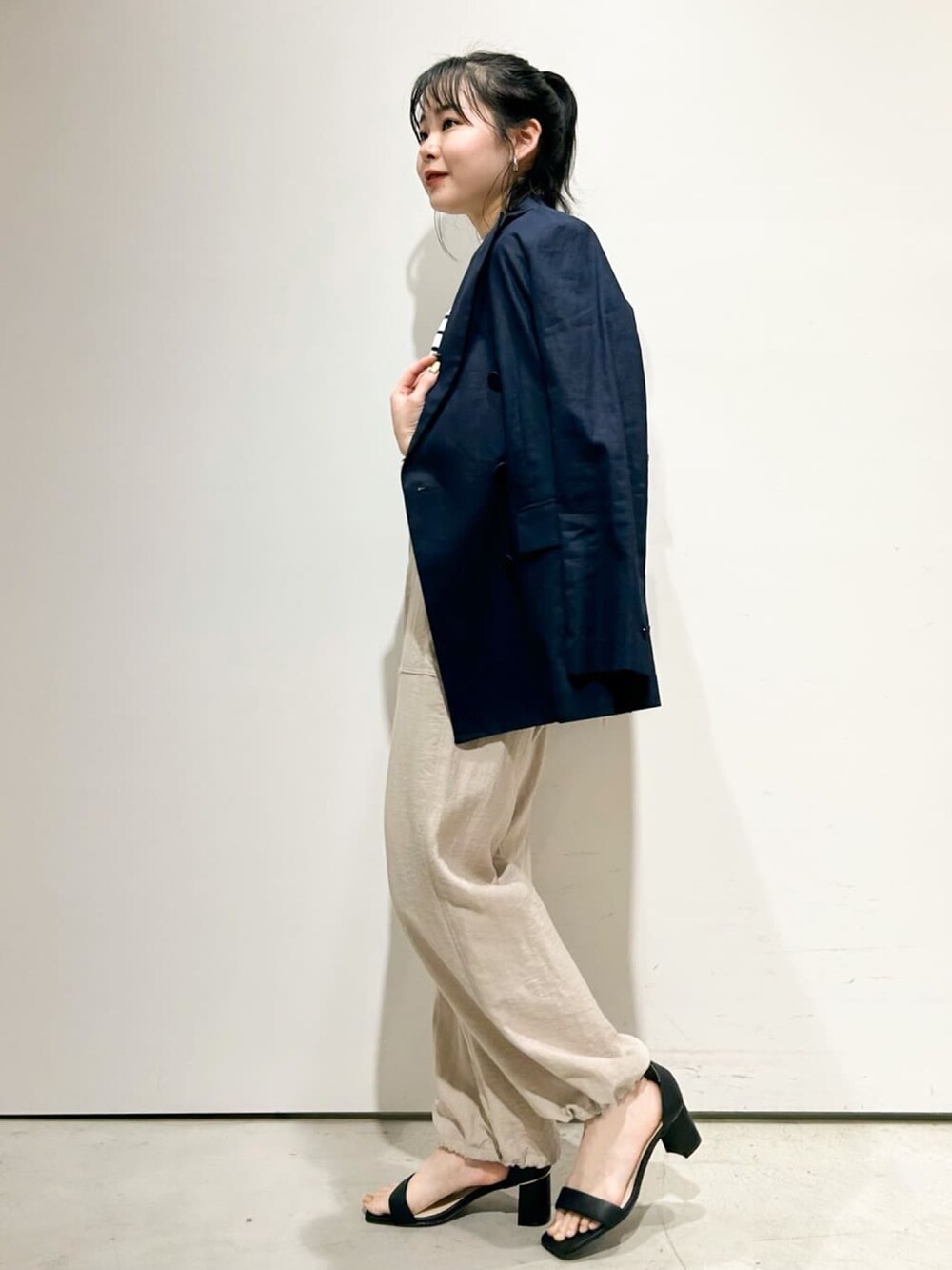 ベージュ系のその他パンツ、ブラック系のサンダル、ホワイト系のニット/セーターを着用したレディースの春コーディネートの2枚目の写真