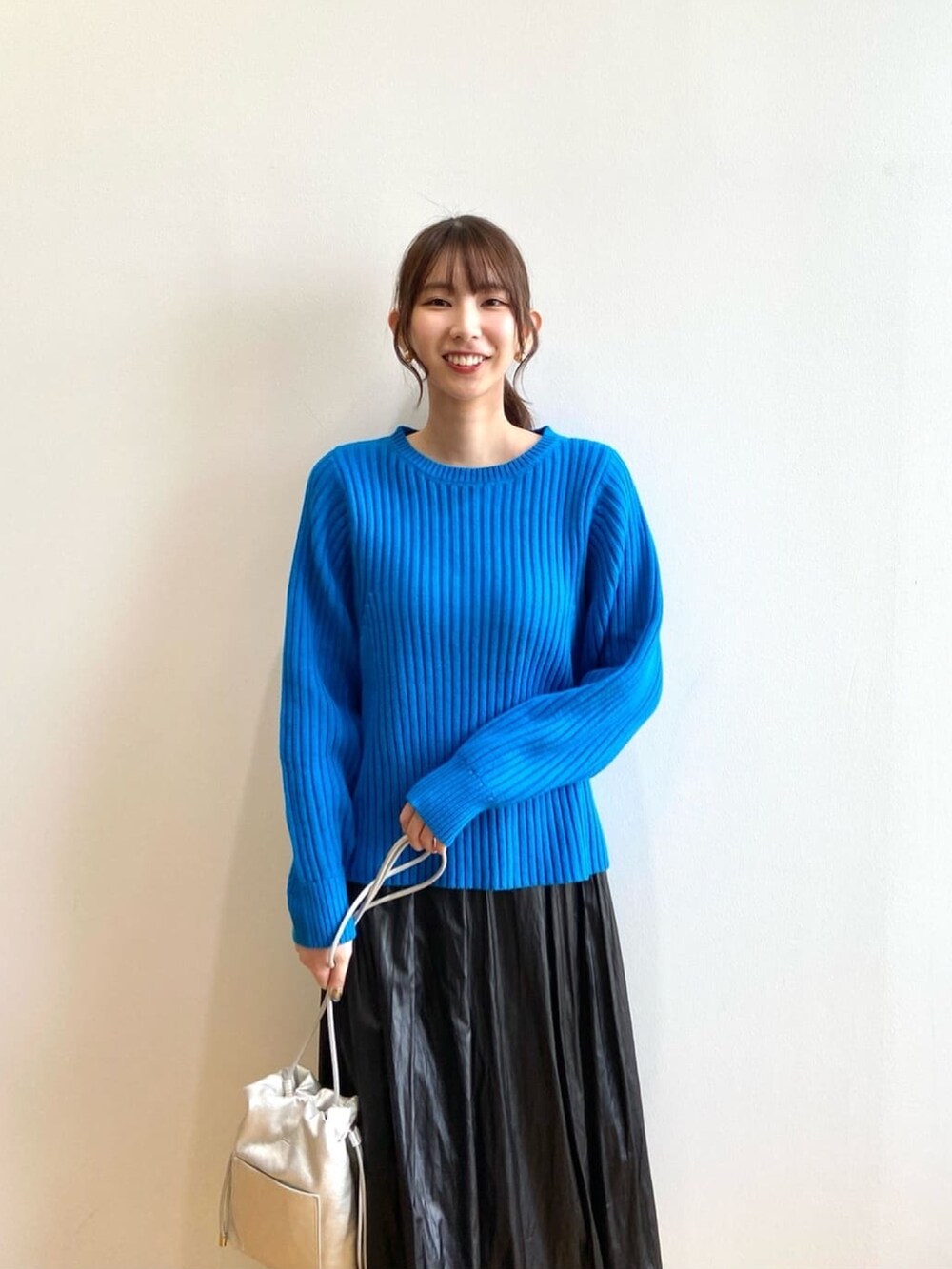 ブルー系のニット/セーター、ブラック系のスカート、ブラック系のブーツを着用したレディースの秋コーディネートの5枚目の写真