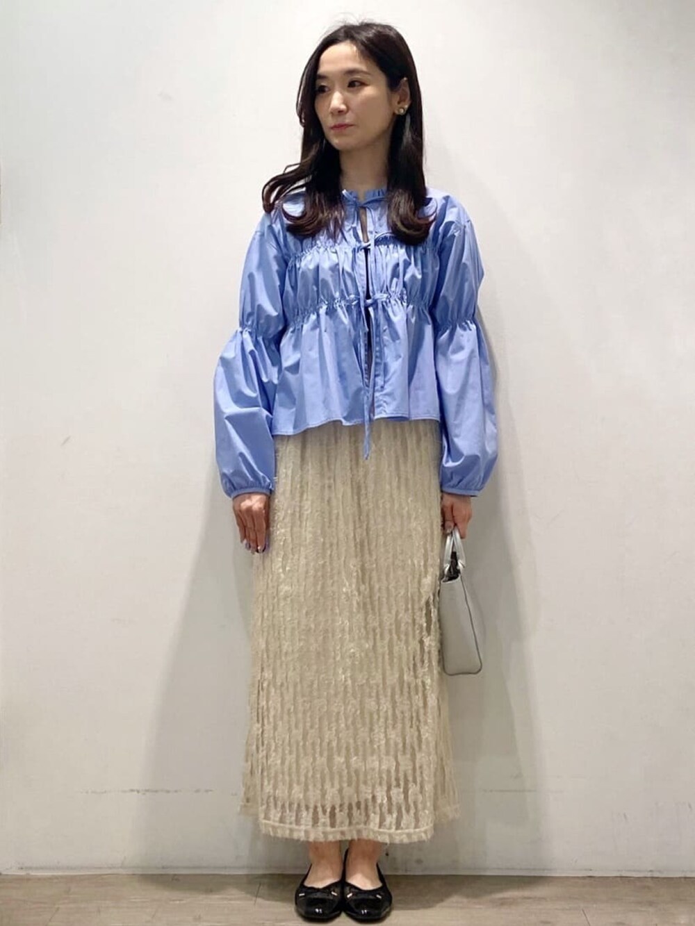 ブルー系のシャツ/ブラウス、ベージュ系のスカート、シルバー系のショルダーバッグを着用したレディースの春コーディネートの2枚目の写真