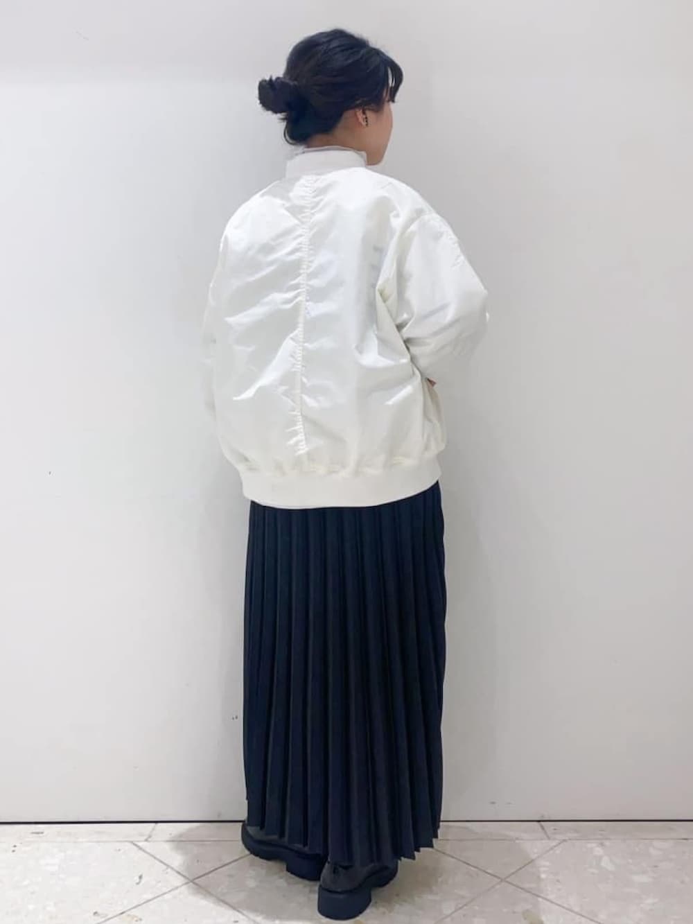 グレー系のスカート、ホワイト系のニット/セーター、ホワイト系のブルゾンを着用したレディースの冬コーディネートの3枚目の写真