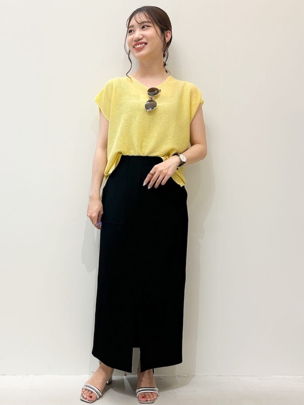 ブラック系のスカート、シルバー系のサンダル、イエロー系のニット/セーターを着用したレディースの夏コーディネートの5枚目の写真