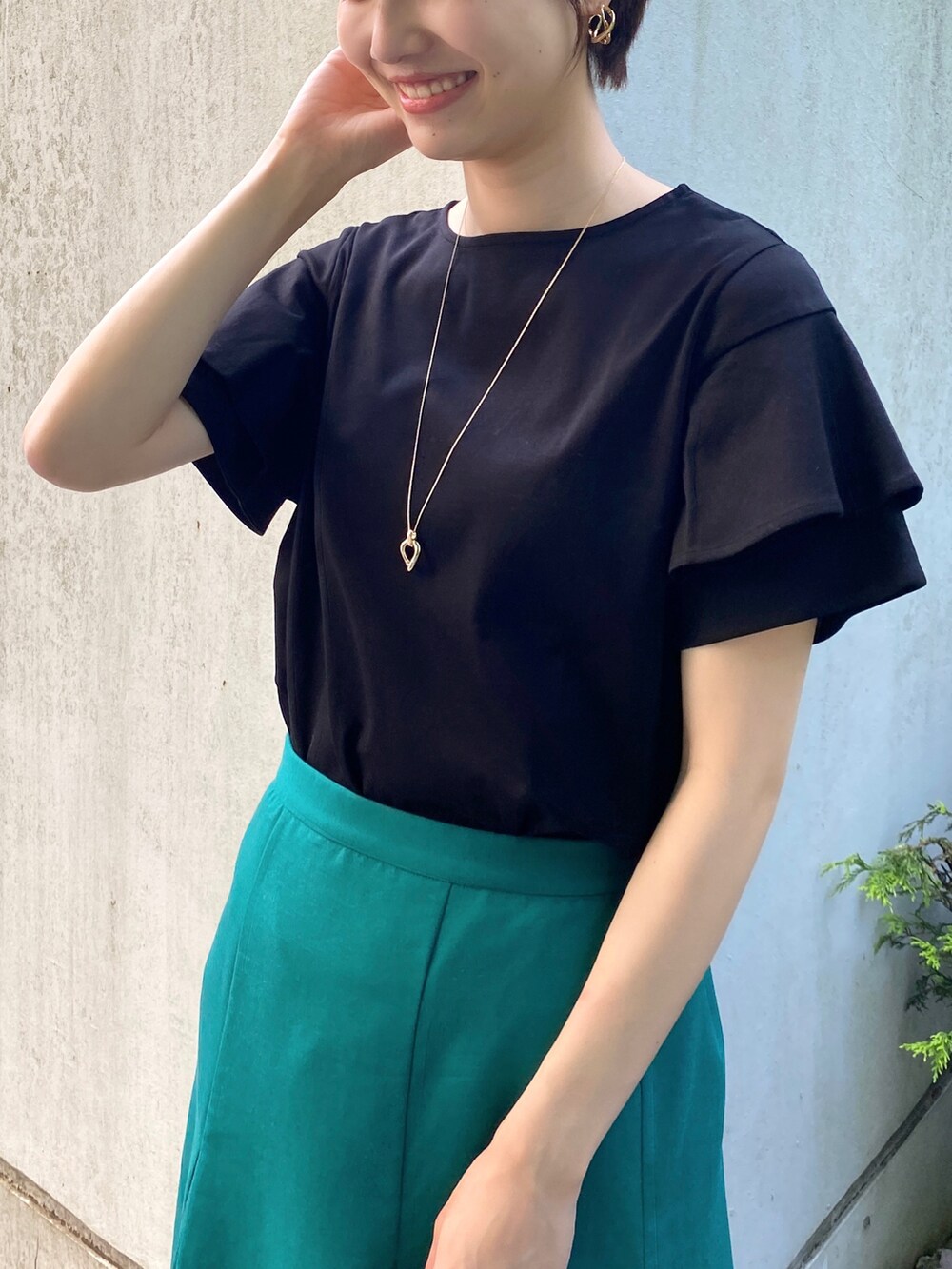 ブラック系のTシャツ/カットソー、グリーン系のスカート、ブラウン系のショルダーバッグを着用したレディースの春コーディネートの3枚目の写真