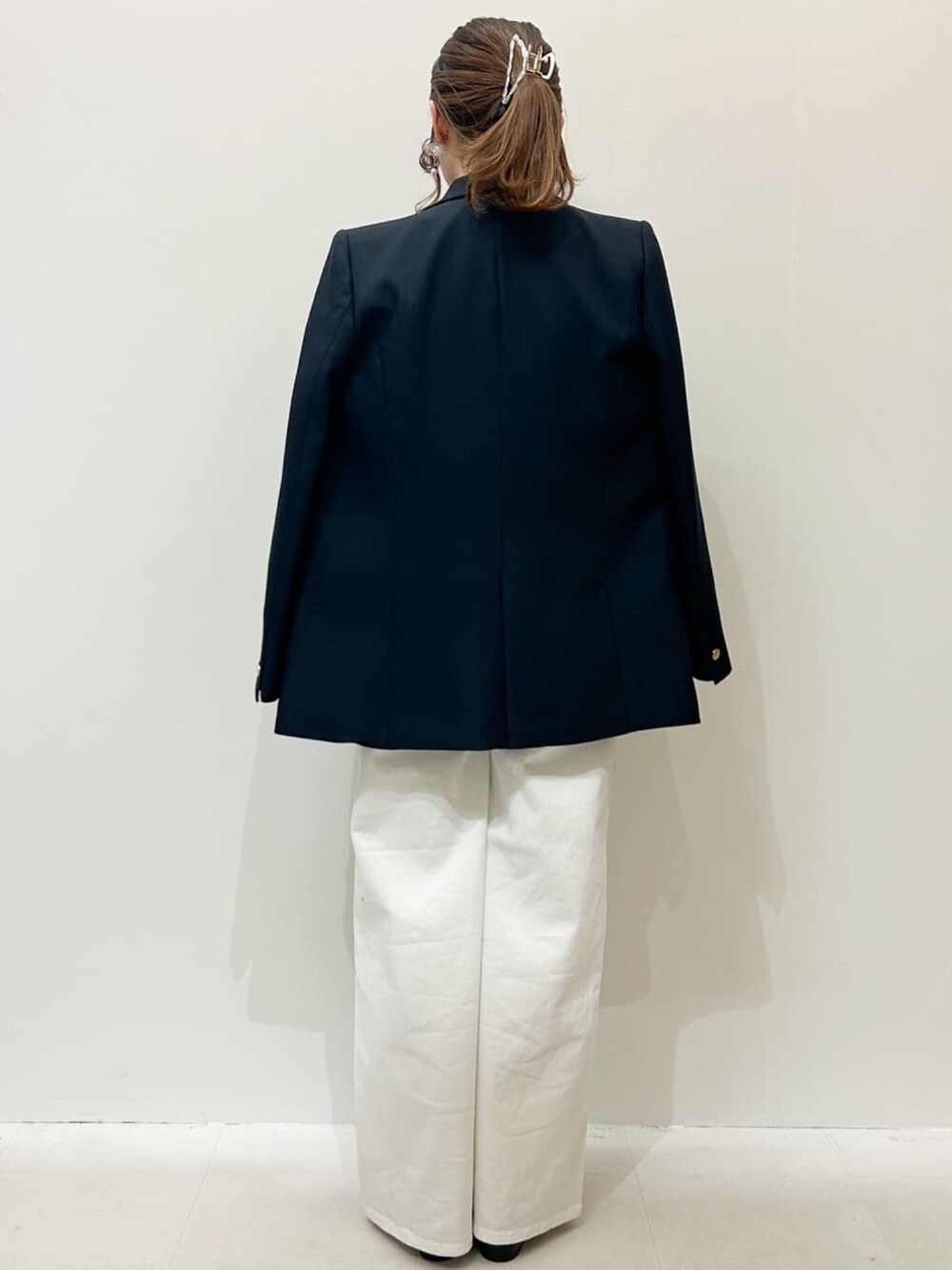 ホワイト系のショルダーバッグ、ホワイト系のデニムパンツ、ブルー系のテーラードジャケットを着用したレディースの冬コーディネートの3枚目の写真