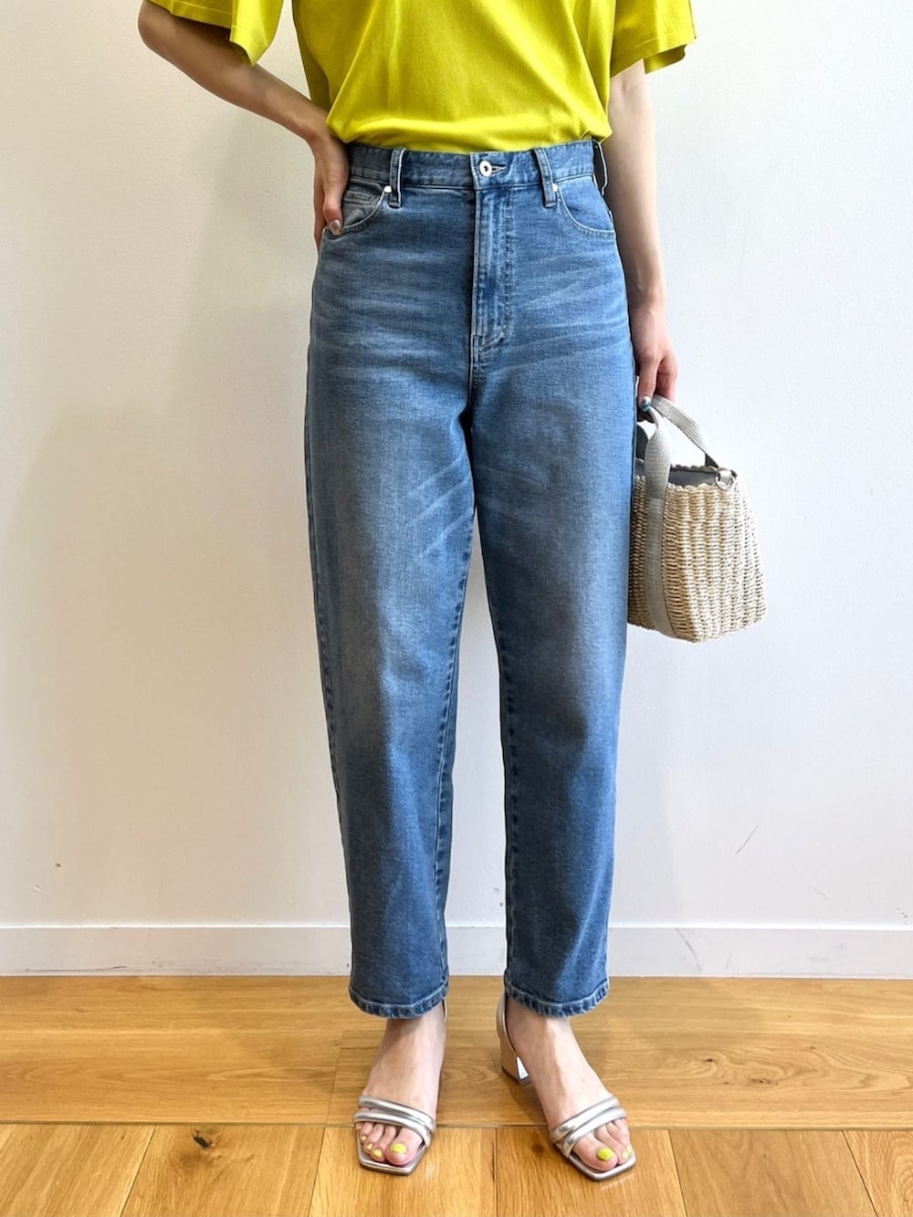 グリーン系のニット/セーター、ブルー系のデニムパンツ、シルバー系のショルダーバッグを着用したレディースの夏コーディネートの6枚目の写真