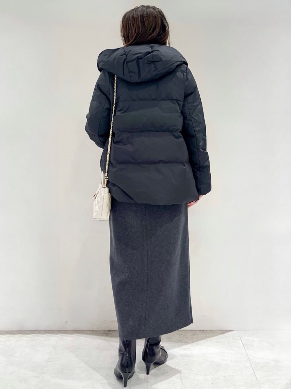 ブラック系のダウンジャケット/コート、グレー系のスカート、ブラック系のブーツを着用したレディースの秋コーディネートの4枚目の写真