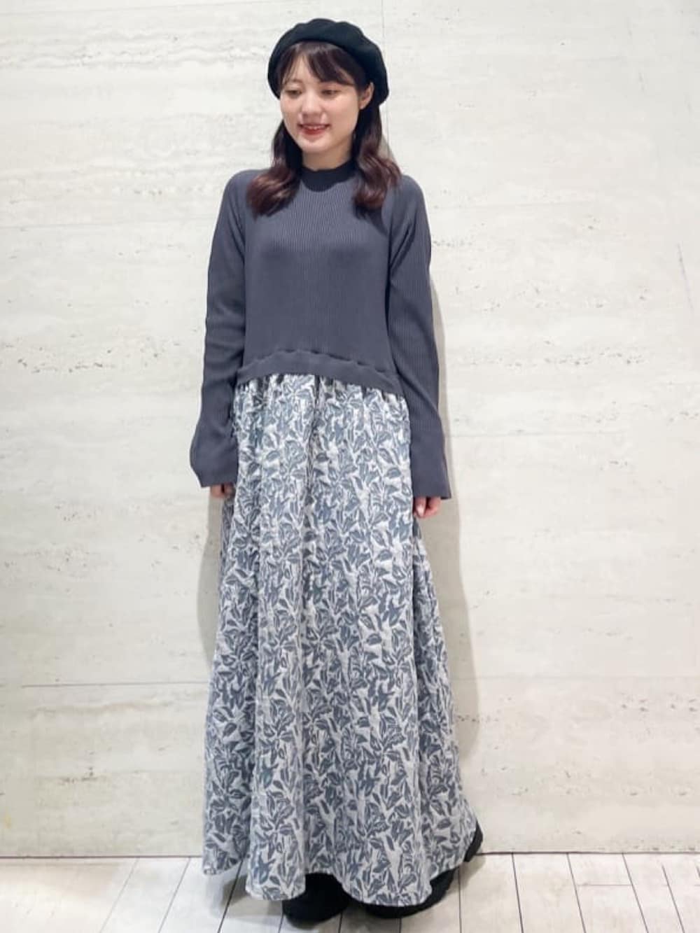 グレー系のベスト、ブルー系のワンピース、ブラック系のブーツを着用したレディースの秋コーディネートの2枚目の写真