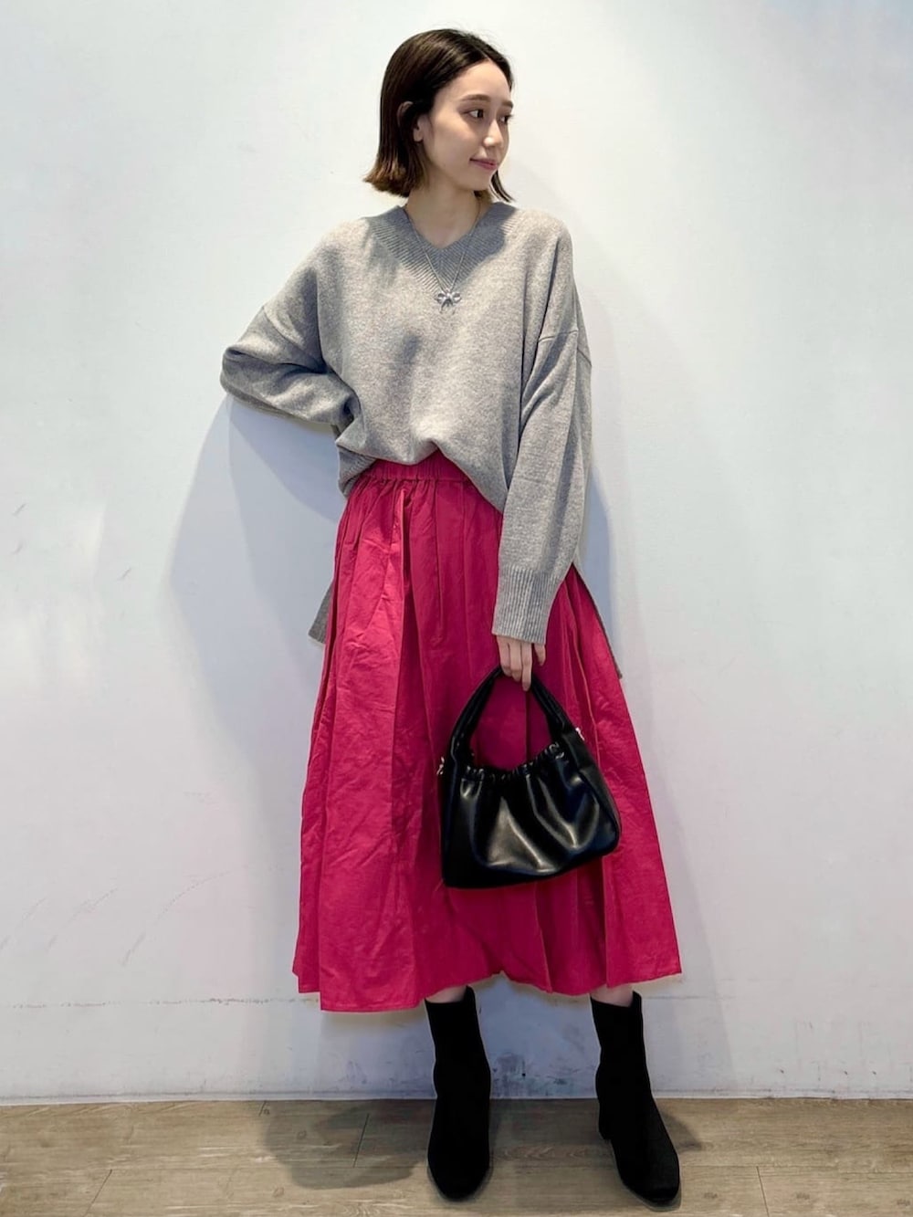 グレー系のニット/セーター、ピンク系のスカート、ブラック系のショルダーバッグを着用したレディースの冬コーディネートの2枚目の写真