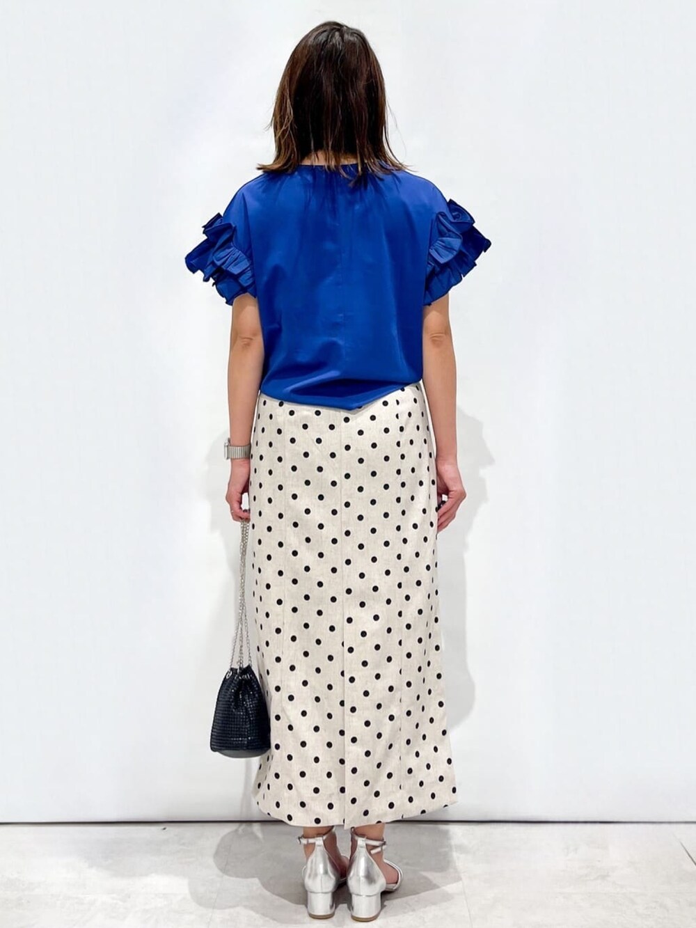 ベージュ系のスカート、ブラック系のショルダーバッグ、シルバー系のサンダルを着用したレディースの夏コーディネートの4枚目の写真