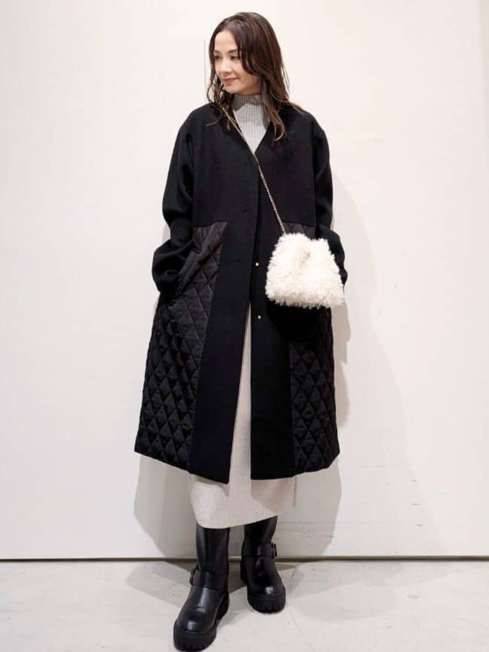 ホワイト系のショルダーバッグ、ブラック系のブーツ、ベージュ系のワンピースを着用したレディースの冬コーディネートの2枚目の写真