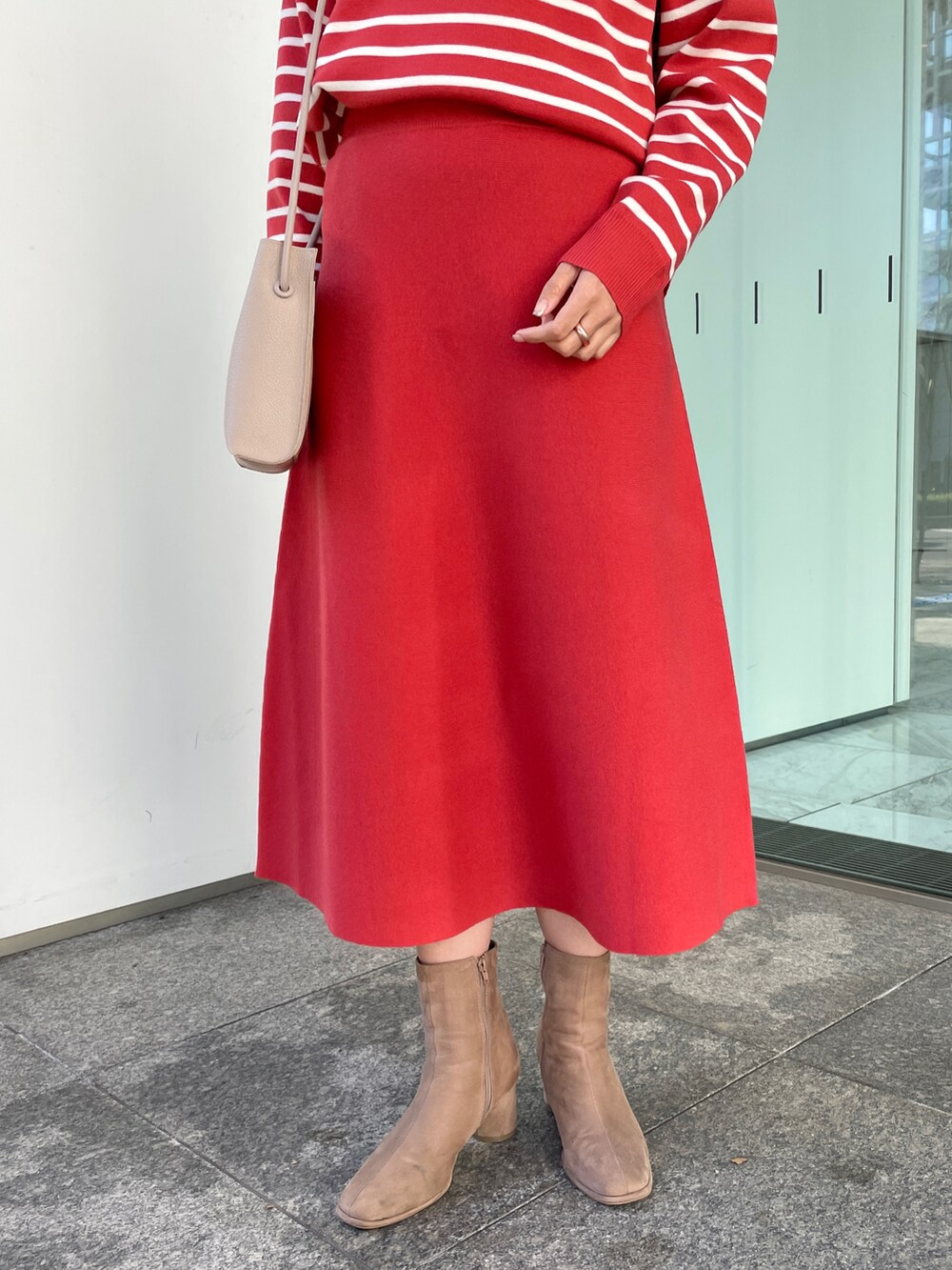 レッド系のニット/セーター、レッド系のスカート、ベージュ系のブーツを着用したレディースの冬コーディネートの5枚目の写真