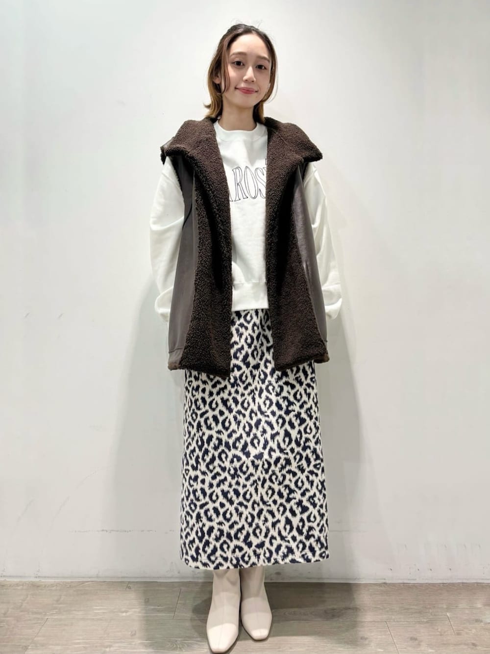 ブルー系のスカート、ブラウン系のベスト、ホワイト系のTシャツ/カットソーを着用したレディースの秋コーディネートの5枚目の写真