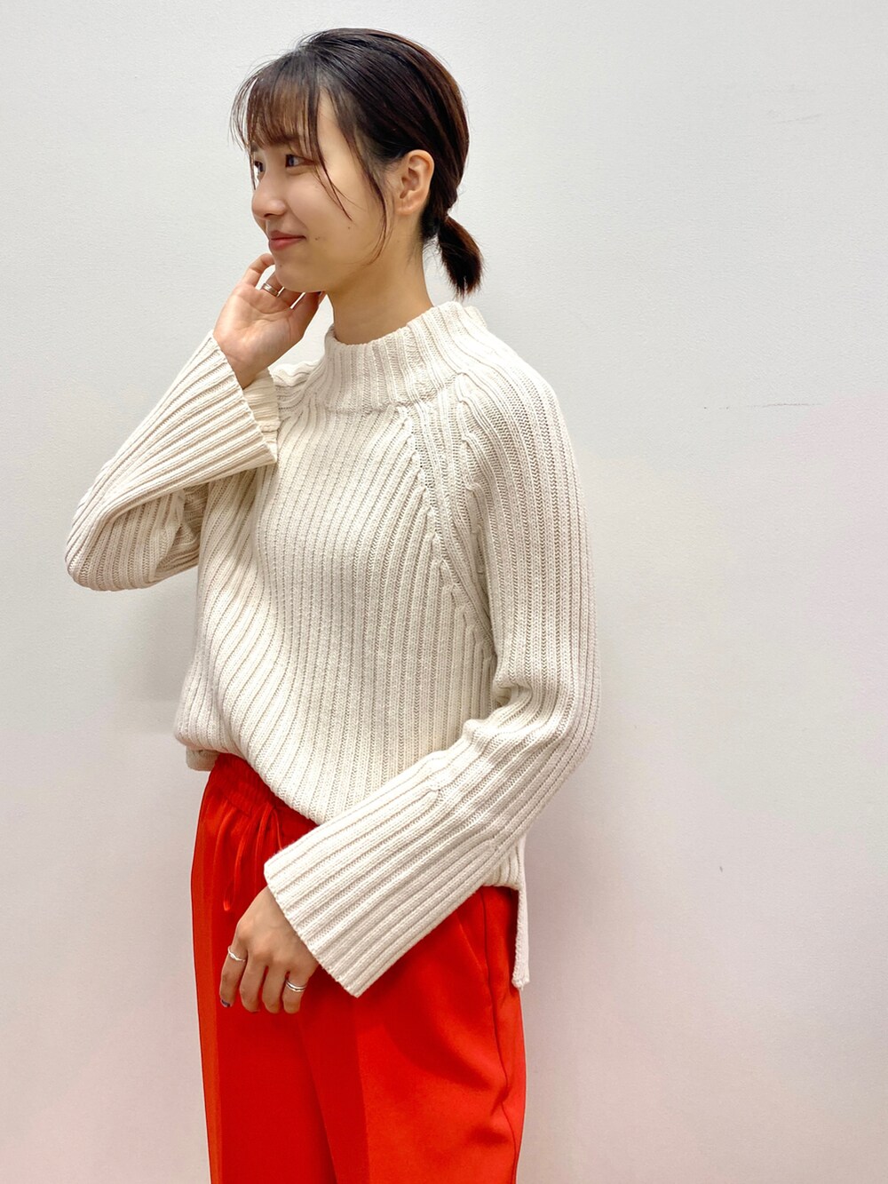 グリーン系のニット/セーター、ベージュ系のノーカラーコート、オレンジ系のその他パンツを着用したレディースの秋コーディネートの4枚目の写真