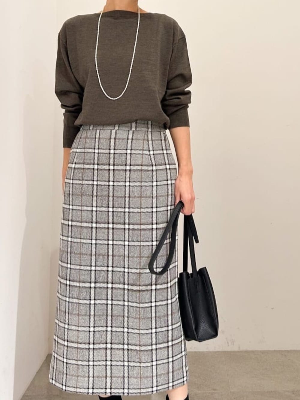 ブラック系のスカート、ブラック系のショルダーバッグ、ブラック系のブーツを着用したレディースの秋コーディネートの3枚目の写真