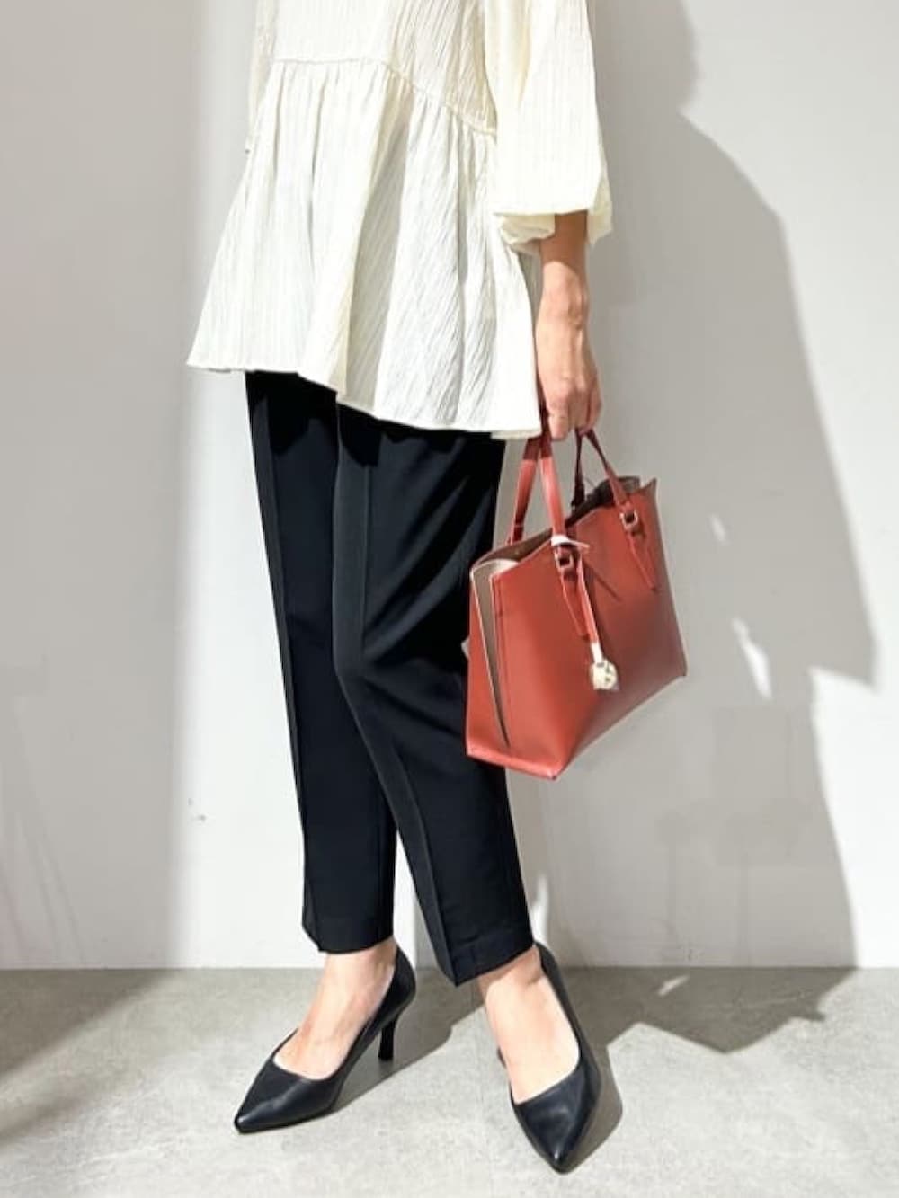 ホワイト系のシャツ/ブラウス、ブラック系のパンプス、レッド系のトートバッグを着用したレディースの夏コーディネートの6枚目の写真