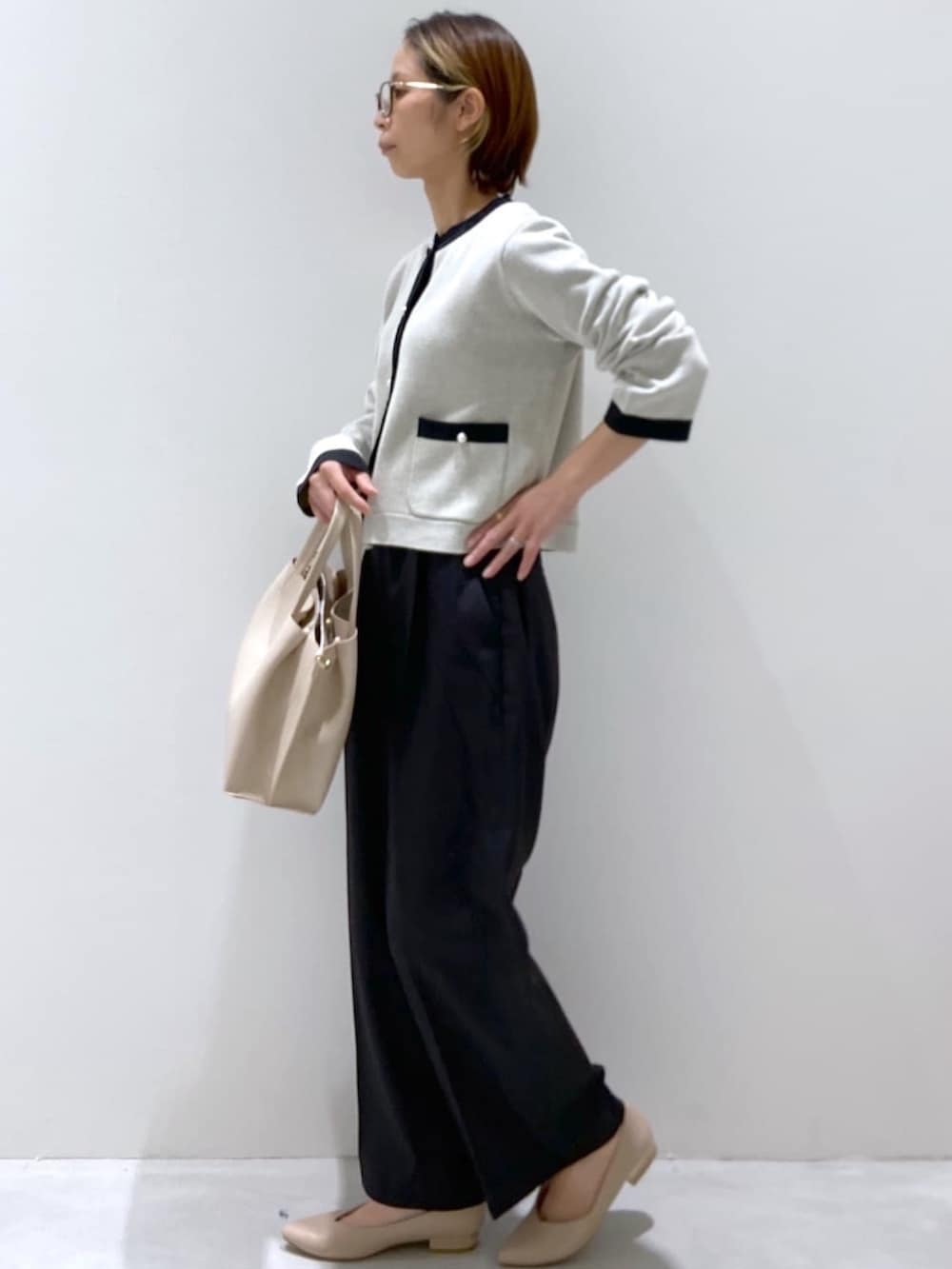 ホワイト系のカーディガン/ボレロ、ブラック系のその他パンツ、ベージュ系のトートバッグを着用したレディースの秋コーディネートの2枚目の写真