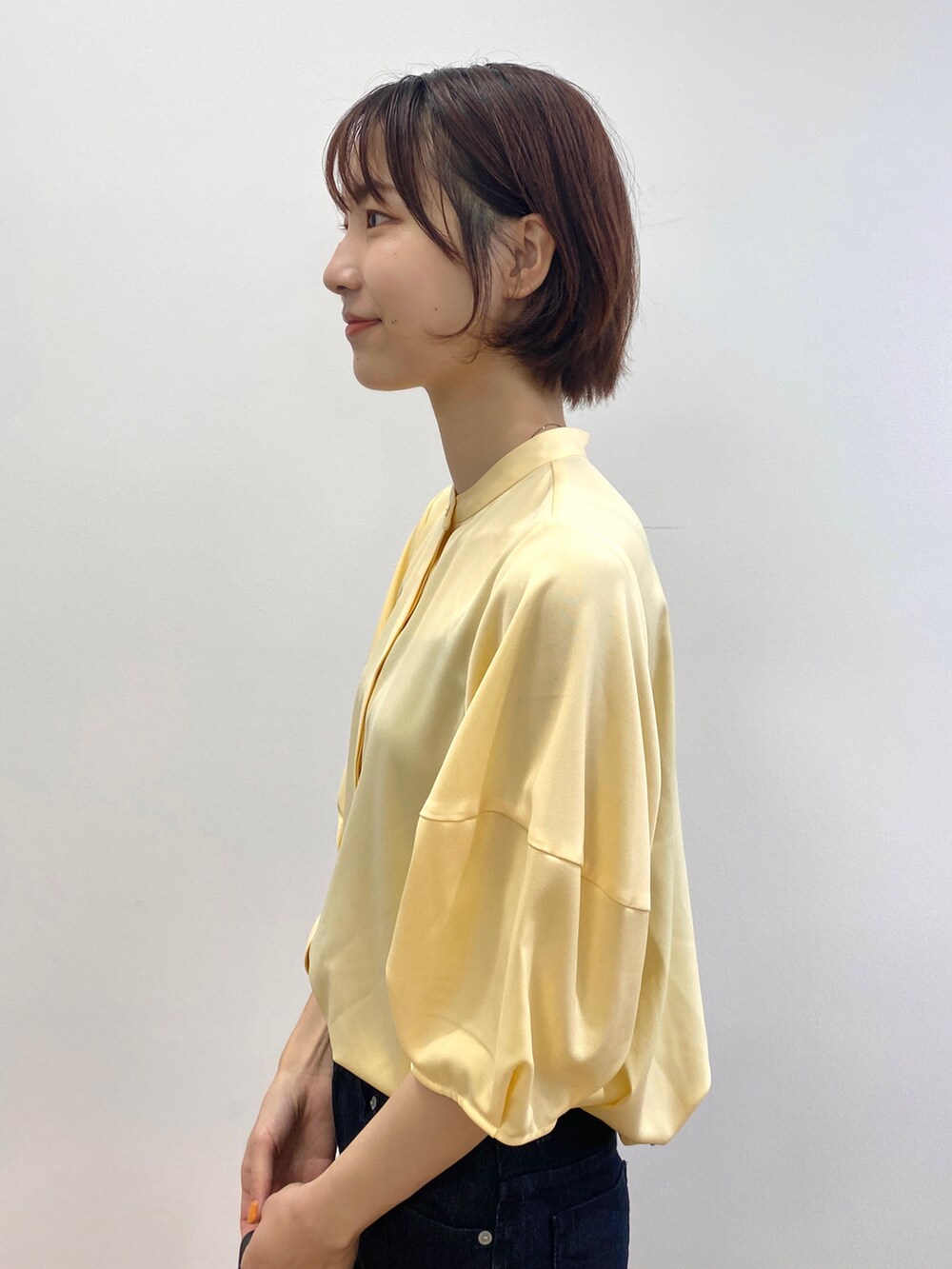 イエロー系のシャツ/ブラウス、ベージュ系のパンプス、ブラック系のハンドバッグを着用したレディースの夏コーディネートの4枚目の写真