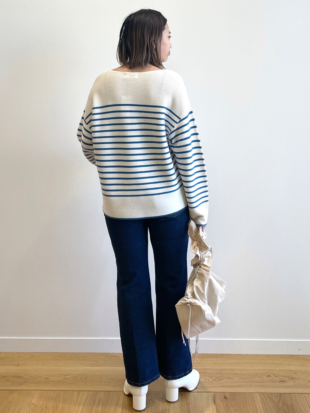 ブルー系のニット/セーター、ブルー系のデニムパンツ、ホワイト系のブーツを着用したレディースの冬コーディネートの3枚目の写真