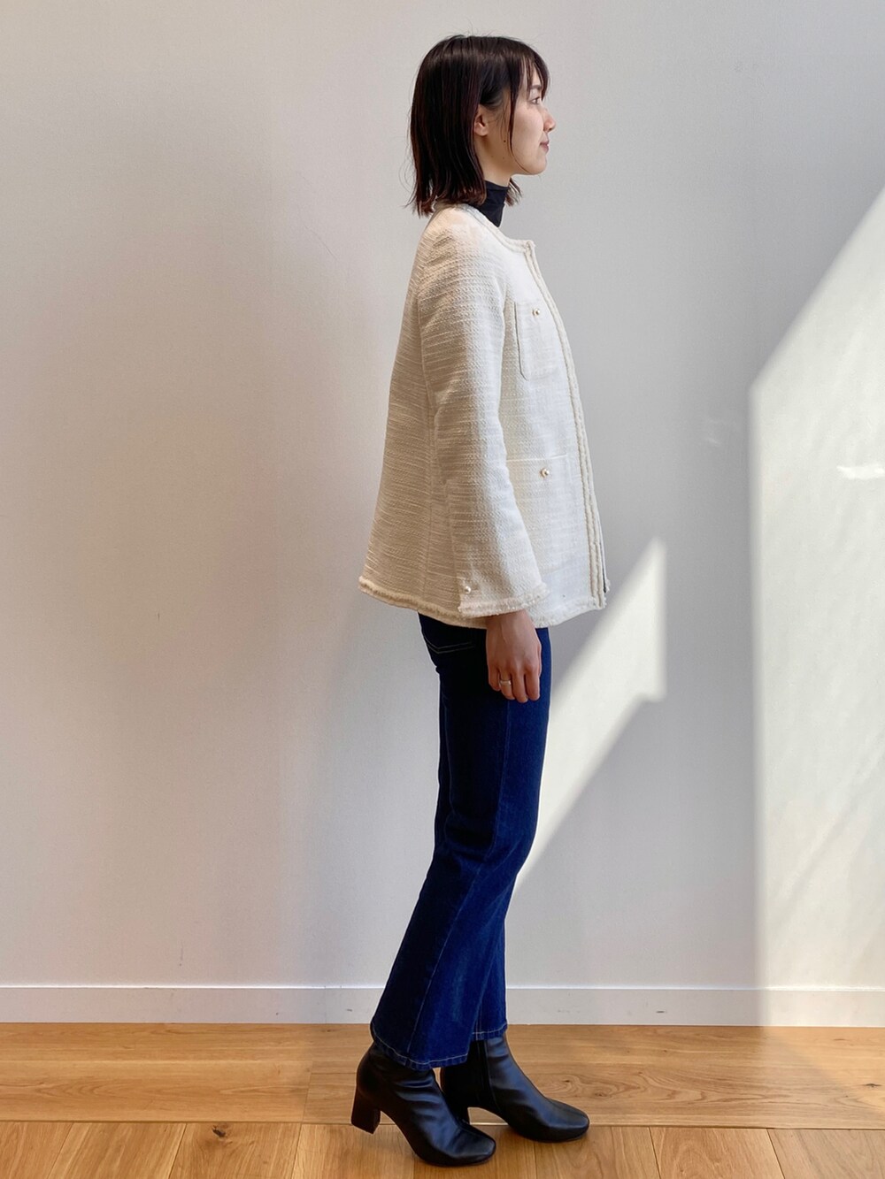 ホワイト系のノーカラージャケット、ブラック系のTシャツ/カットソー、ブラック系のブーツを着用したレディースの冬コーディネートの3枚目の写真