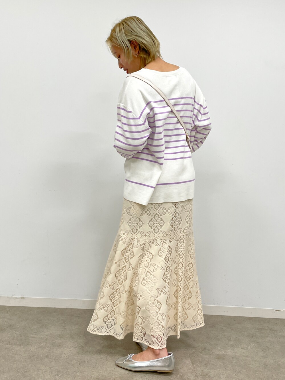 パープル系のニット/セーター、ホワイト系のスカート、ホワイト系のショルダーバッグを着用したレディースの冬コーディネートの2枚目の写真