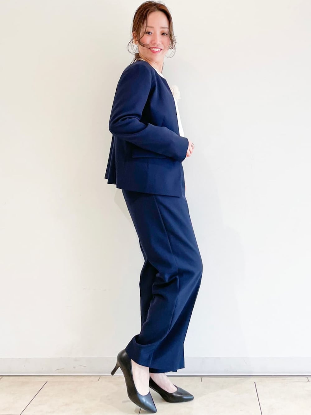 ブラック系のパンプス、ベージュ系のトレンチコート、ブルー系のスーツパンツを着用したレディースの春コーディネートの3枚目の写真