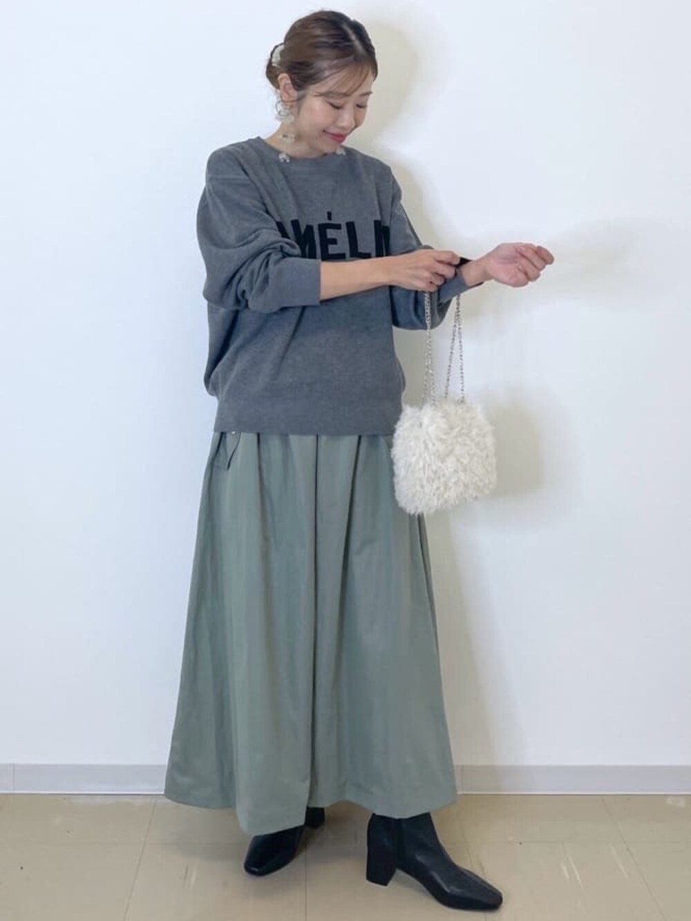 グレー系のニット/セーター、グリーン系のスカート、ホワイト系のショルダーバッグを着用したレディースの冬コーディネートの2枚目の写真