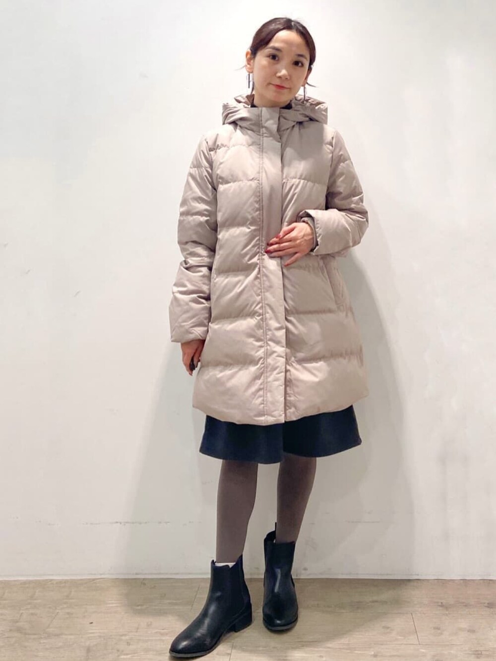 ベージュ系のダウンジャケット/コート、グレー系のワンピース、ブラック系のブーツを着用したレディースの冬コーディネートの2枚目の写真
