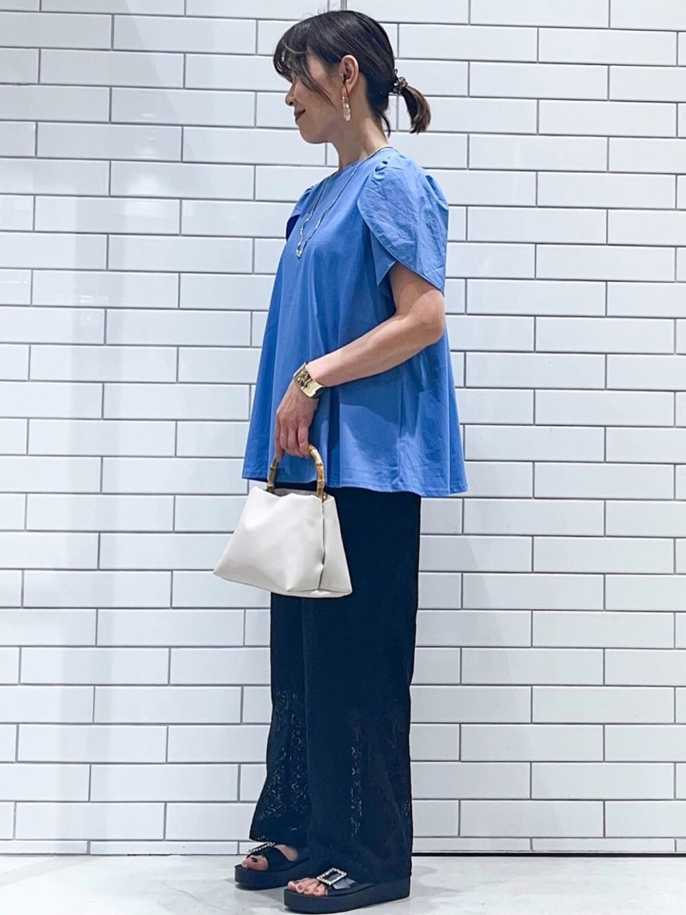 ブルー系のTシャツ/カットソー、ブラック系のサンダル、ホワイト系のショルダーバッグを着用したレディースの春コーディネートの2枚目の写真