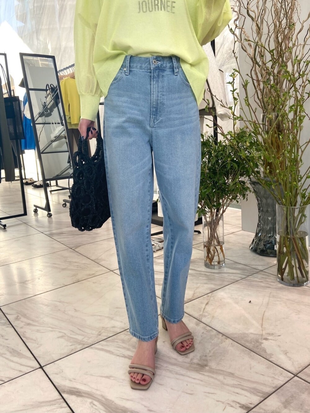 グリーン系のニット/セーター、ブルー系のデニムパンツ、ベージュ系のサンダルを着用したレディースの春コーディネートの7枚目の写真