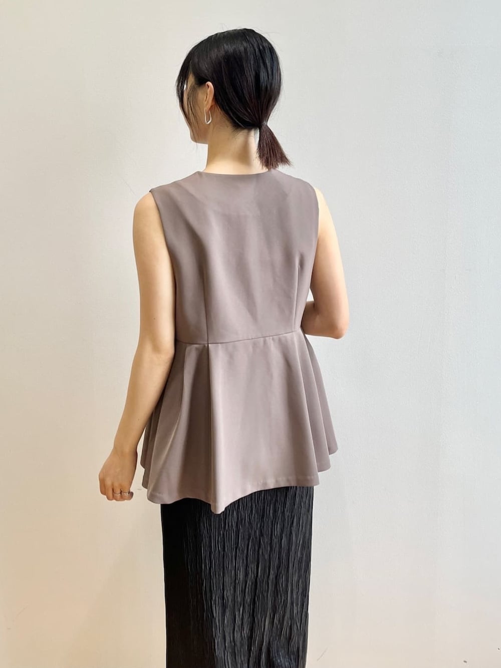 ホワイト系のタンクトップ、ホワイト系のサンダル、ブラウン系のベストを着用したレディースの夏コーディネートの7枚目の写真