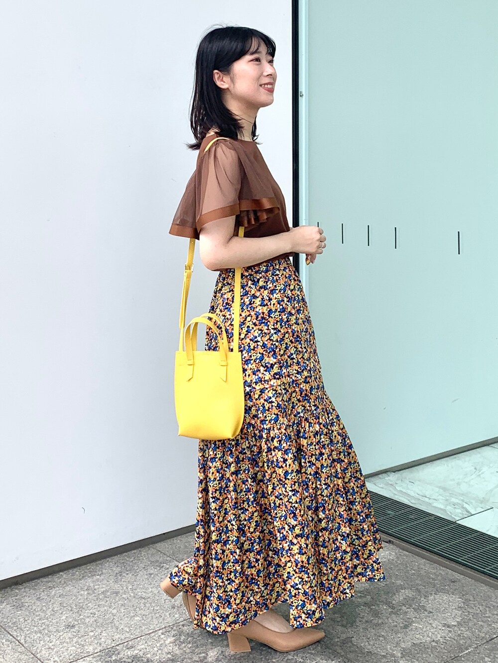 ブラウン系のTシャツ/カットソー、オレンジ系のスカート、イエロー系のショルダーバッグを着用したレディースの夏コーディネートの2枚目の写真