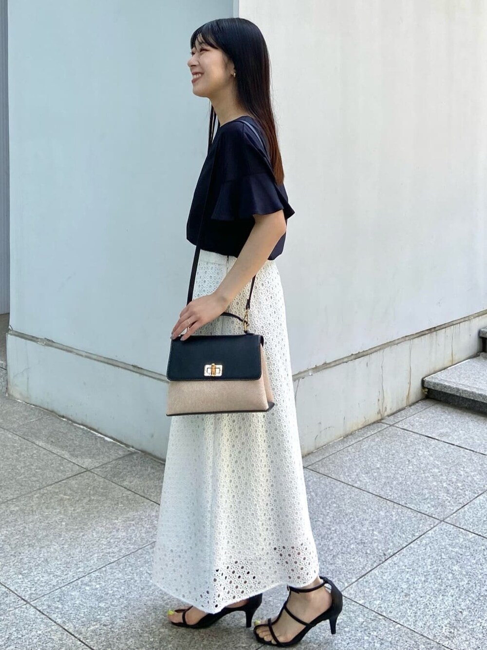 ブラック系のTシャツ/カットソー、ホワイト系のスカート、ブラック系のサンダルを着用したレディースの春コーディネートの2枚目の写真