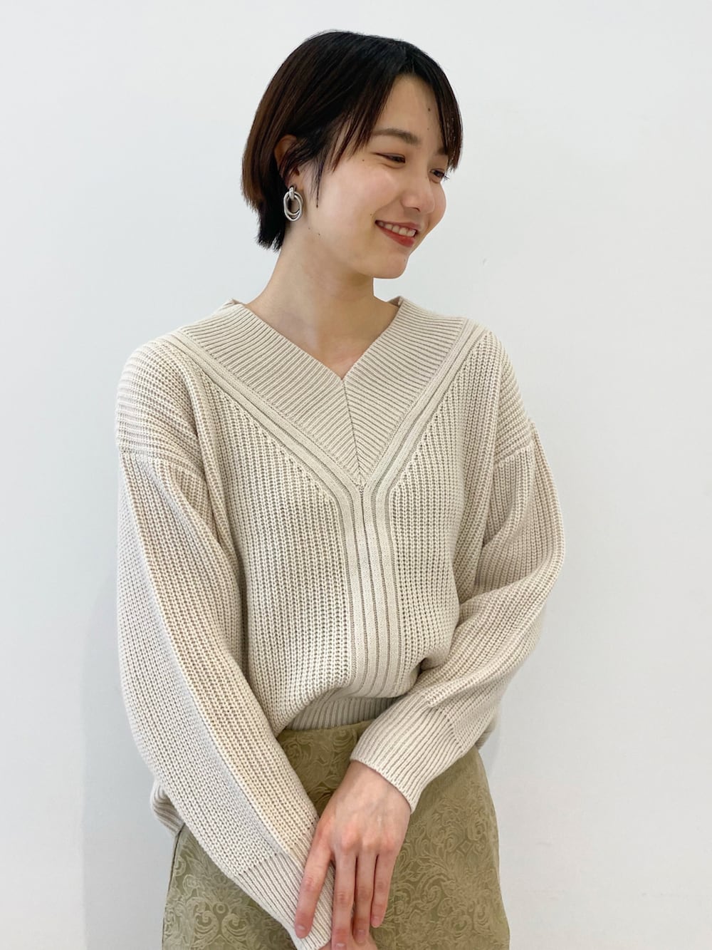 ホワイト系のニット/セーター、グレー系のショルダーバッグ、ベージュ系のスカートを着用したレディースの冬コーディネートの2枚目の写真