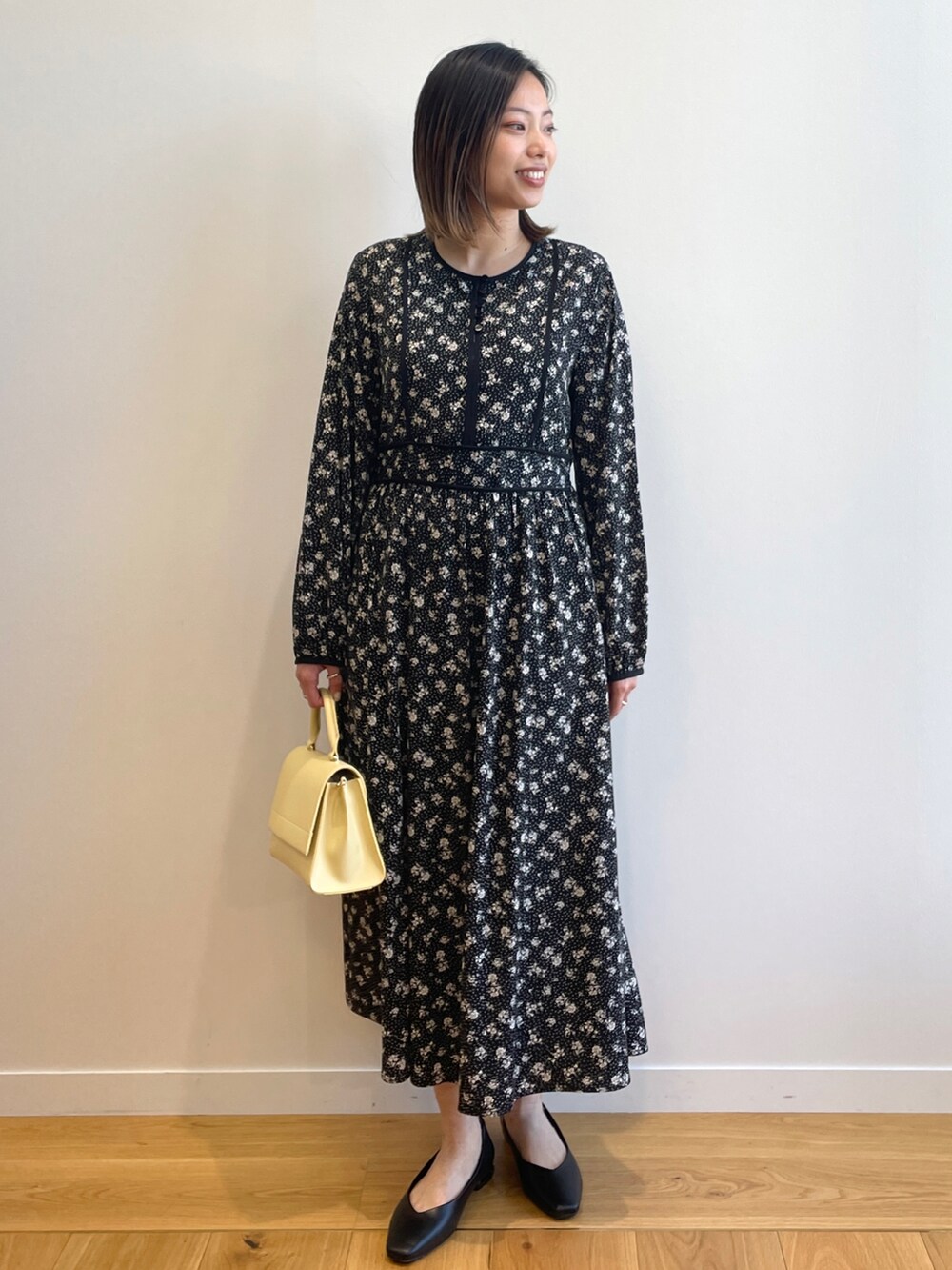 ベージュ系のノーカラージャケット、ブラック系のワンピース、イエロー系のショルダーバッグを着用したレディースの春コーディネートの5枚目の写真